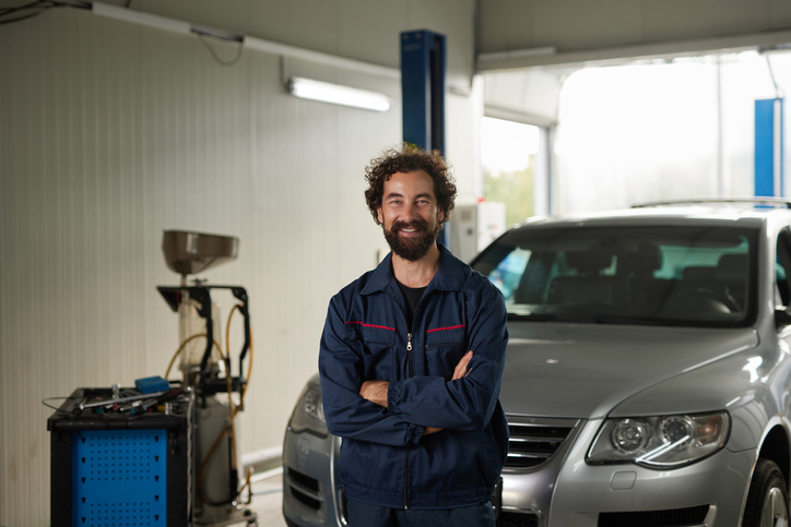 Smiling mechanic with arms crossed in repair shop