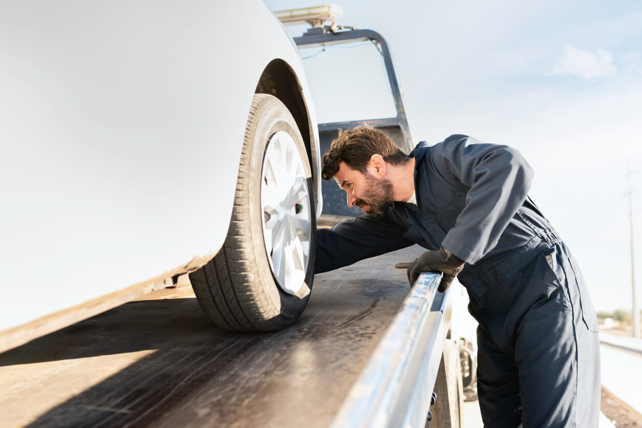 Tow truck worker securing a car on the platform.