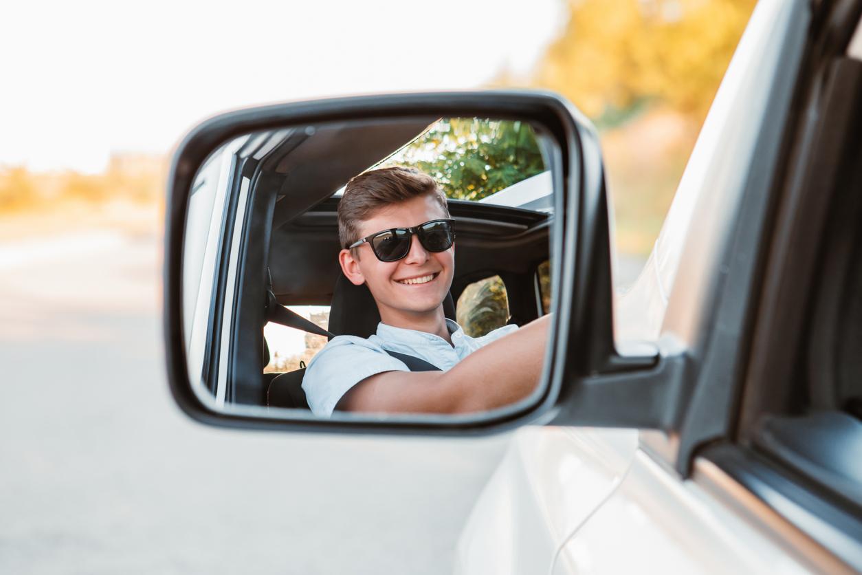 A teen male driving a car.