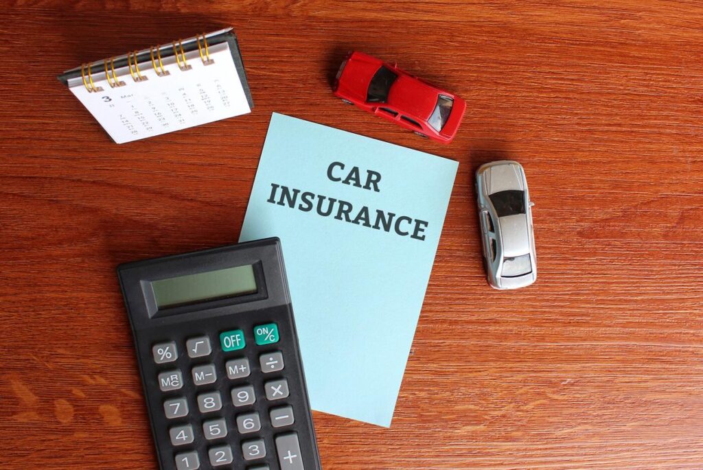 Planning and financial concept. Top view of desk calendar, calculator, miniature car and paper with text “CAR INSURANCE”