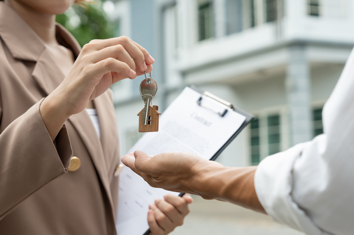 Landlord holding signed contract handing keys to tenant